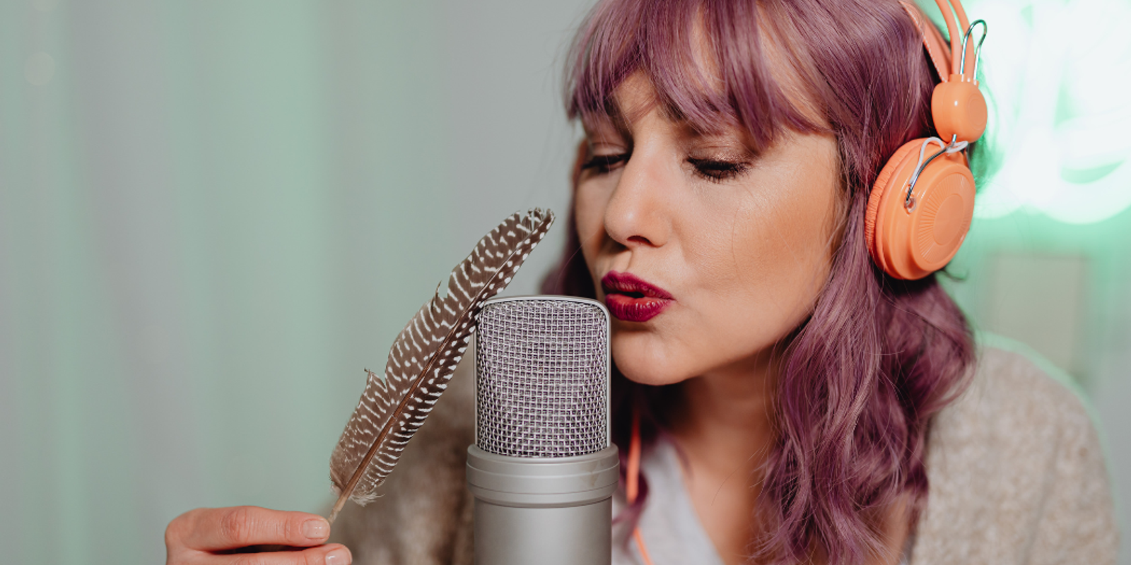 A woman with a feather blowing into a microphone